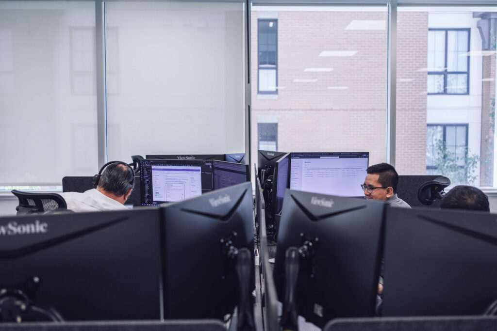 Two coworkers sit at their work stations