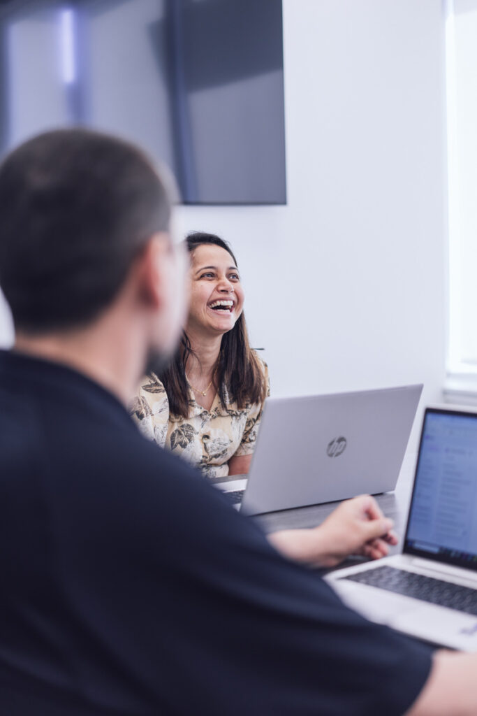 Coworkers sitting at a boardroom table laughing