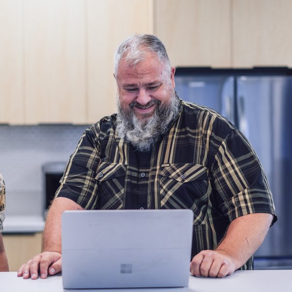 An employee standing in the office kitchen smiling