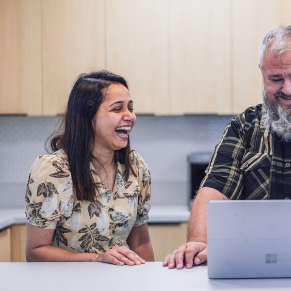 Two coworkers standing talking in the office kitchen