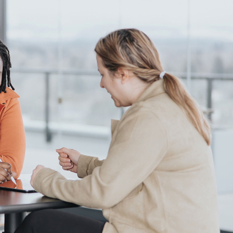 An employee sitting at a table with a coworker looking at a tablet