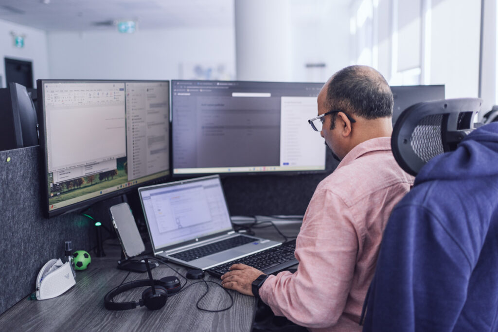 An employee sitting at their workstation on their laptop