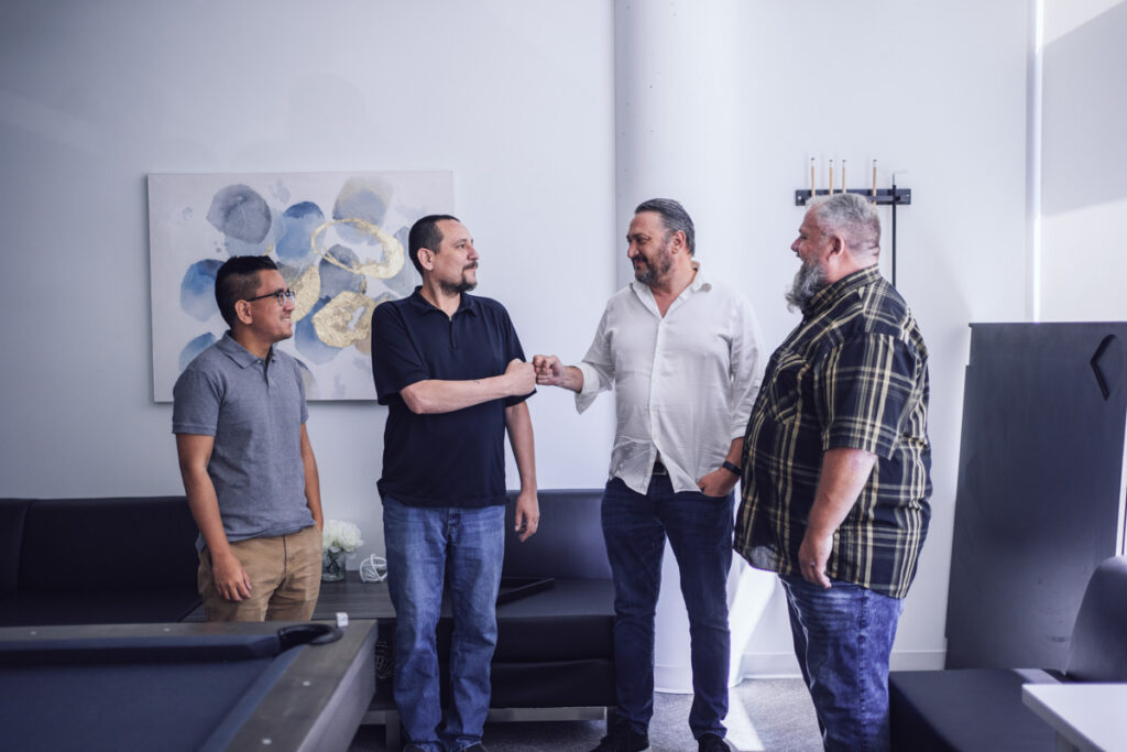 Four coworkers stand chatting in an office