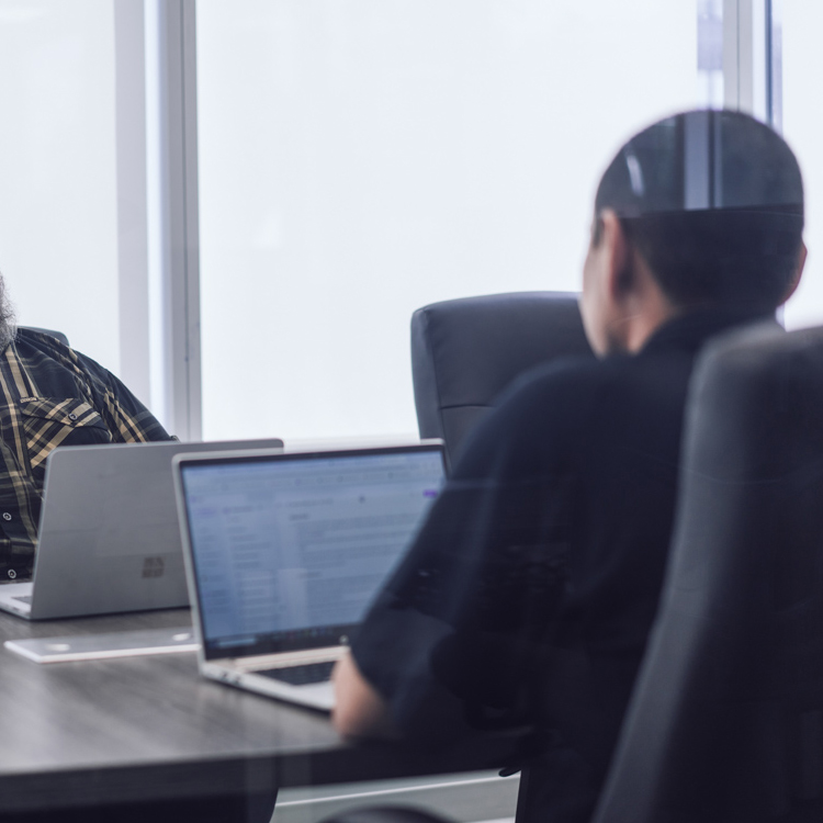 two coworkers on laptops in the boardroom