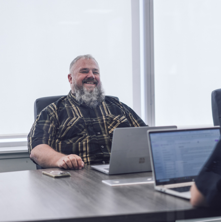 two coworkers on laptops in the boardroom